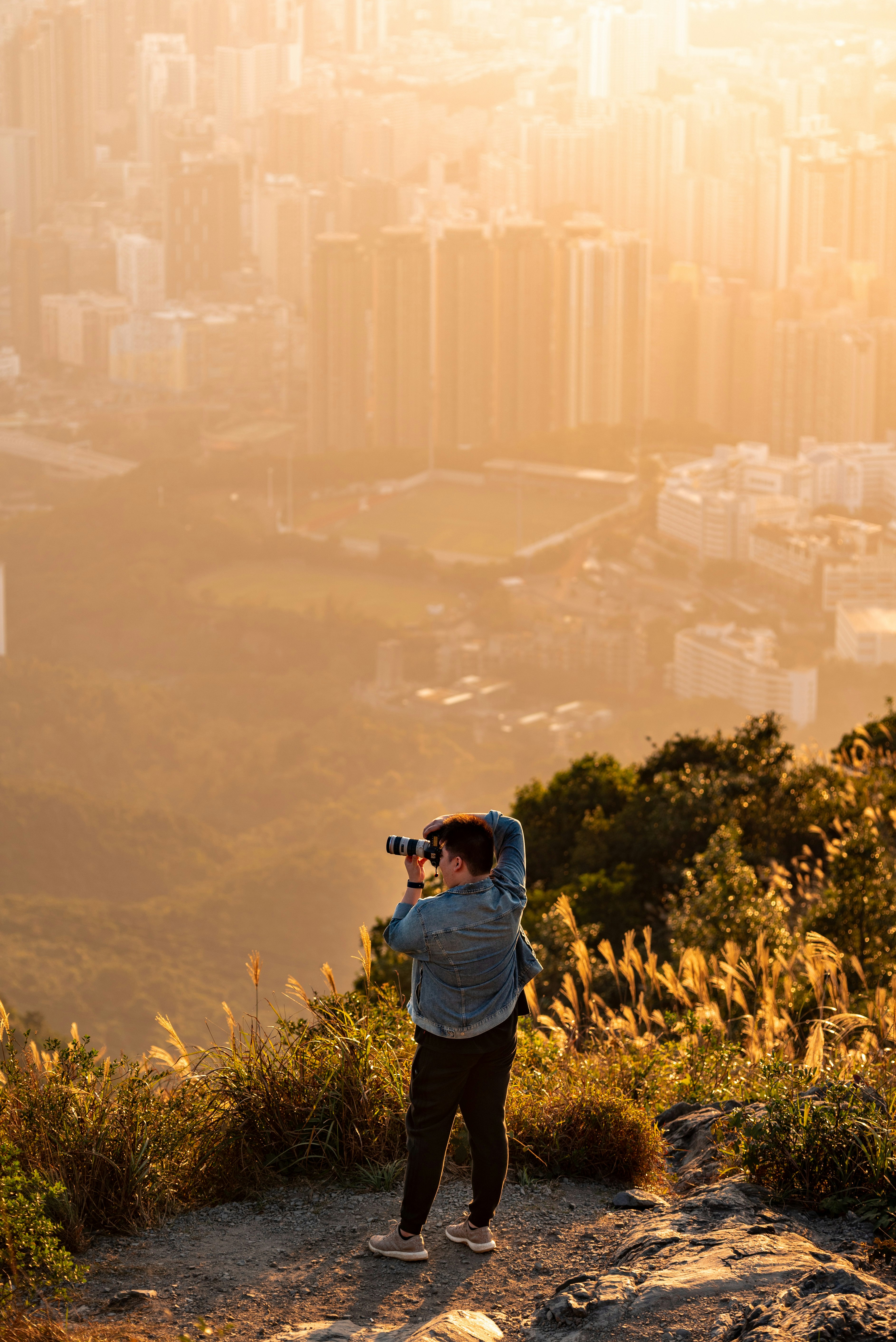 man in blue jacket taking photo of city during daytime