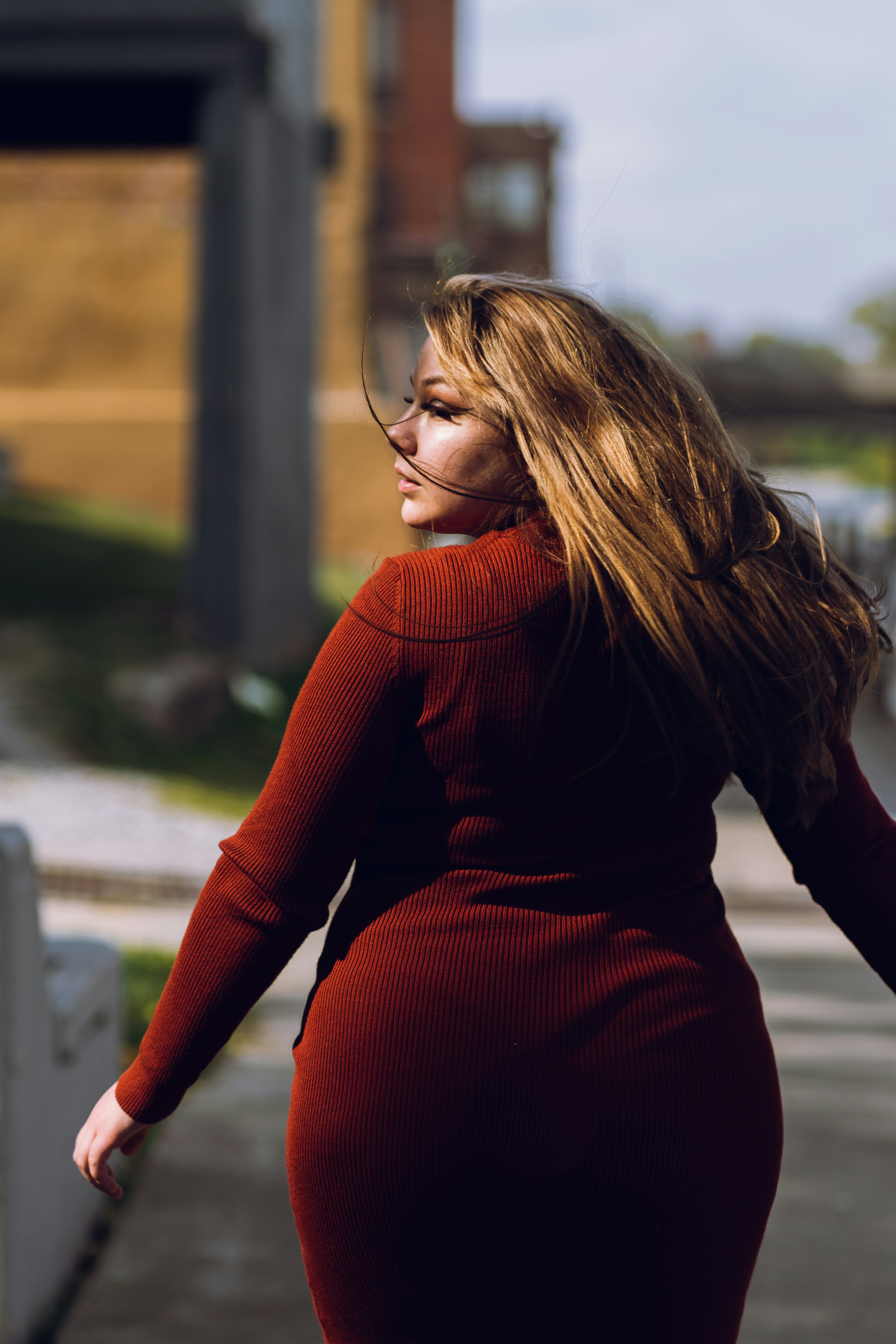 woman in red sweater and black pants standing near railings during daytime