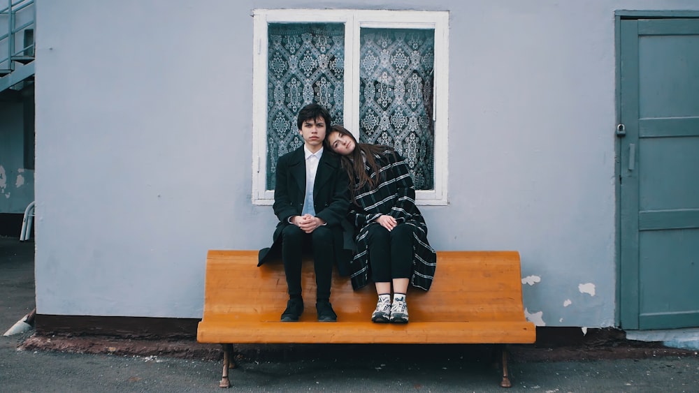 man and woman sitting on brown wooden bench