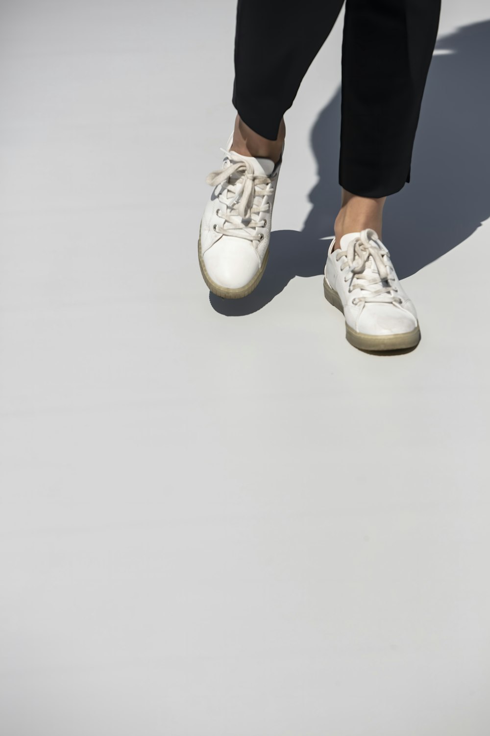 person in black pants and white sneakers