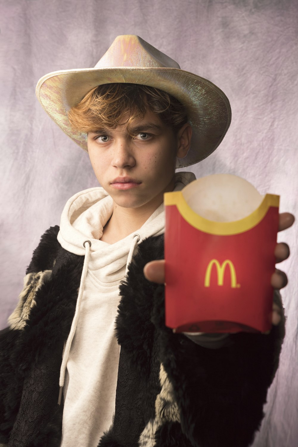 man in black and white fur coat holding red and white mcdonalds cup