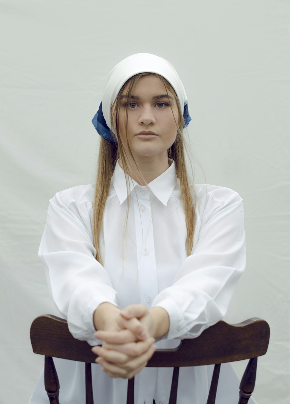 Femme en chemise blanche à manches longues assise sur une chaise en bois marron