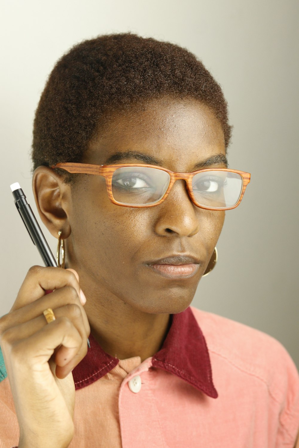 woman in red collared shirt wearing eyeglasses holding pen