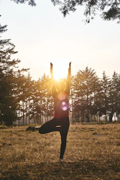woman in black pants and pink shirt standing on green grass field during daytime