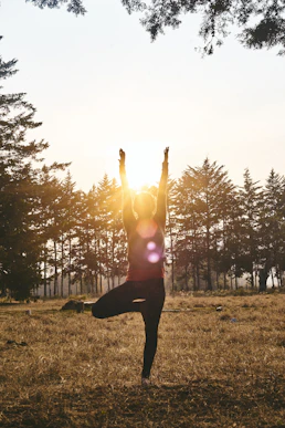 woman in black pants and pink shirt standing on green grass field during daytime