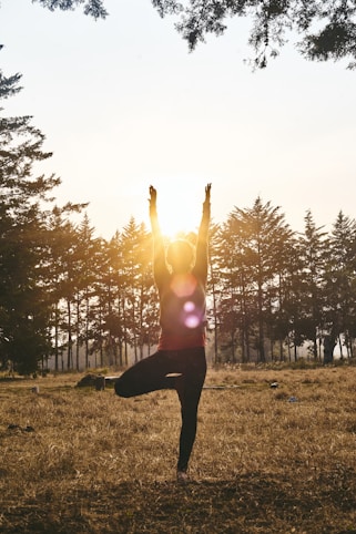 woman in black pants and pink shirt standing on green grass field during daytime