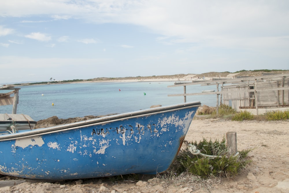 Barco azul y blanco en la orilla del mar durante el día