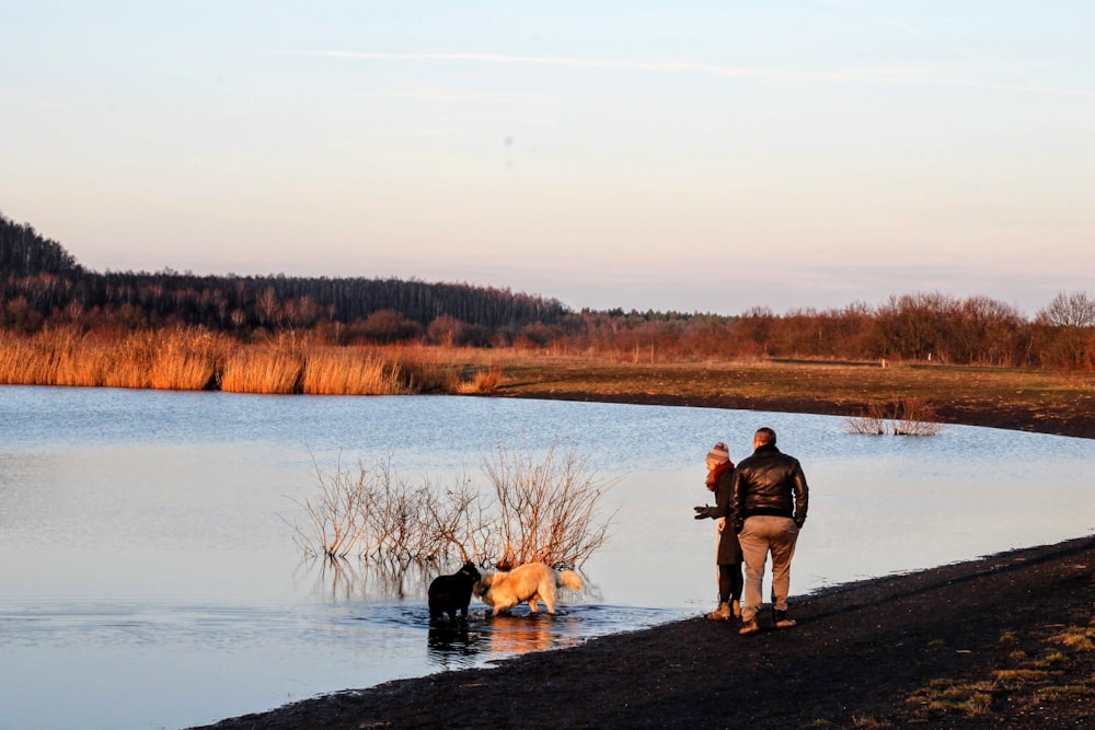 2 men standing on lake shore during daytime