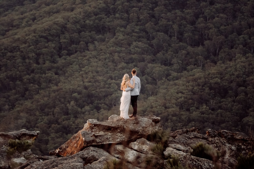 man in white dress shirt standing on brown rock during daytime