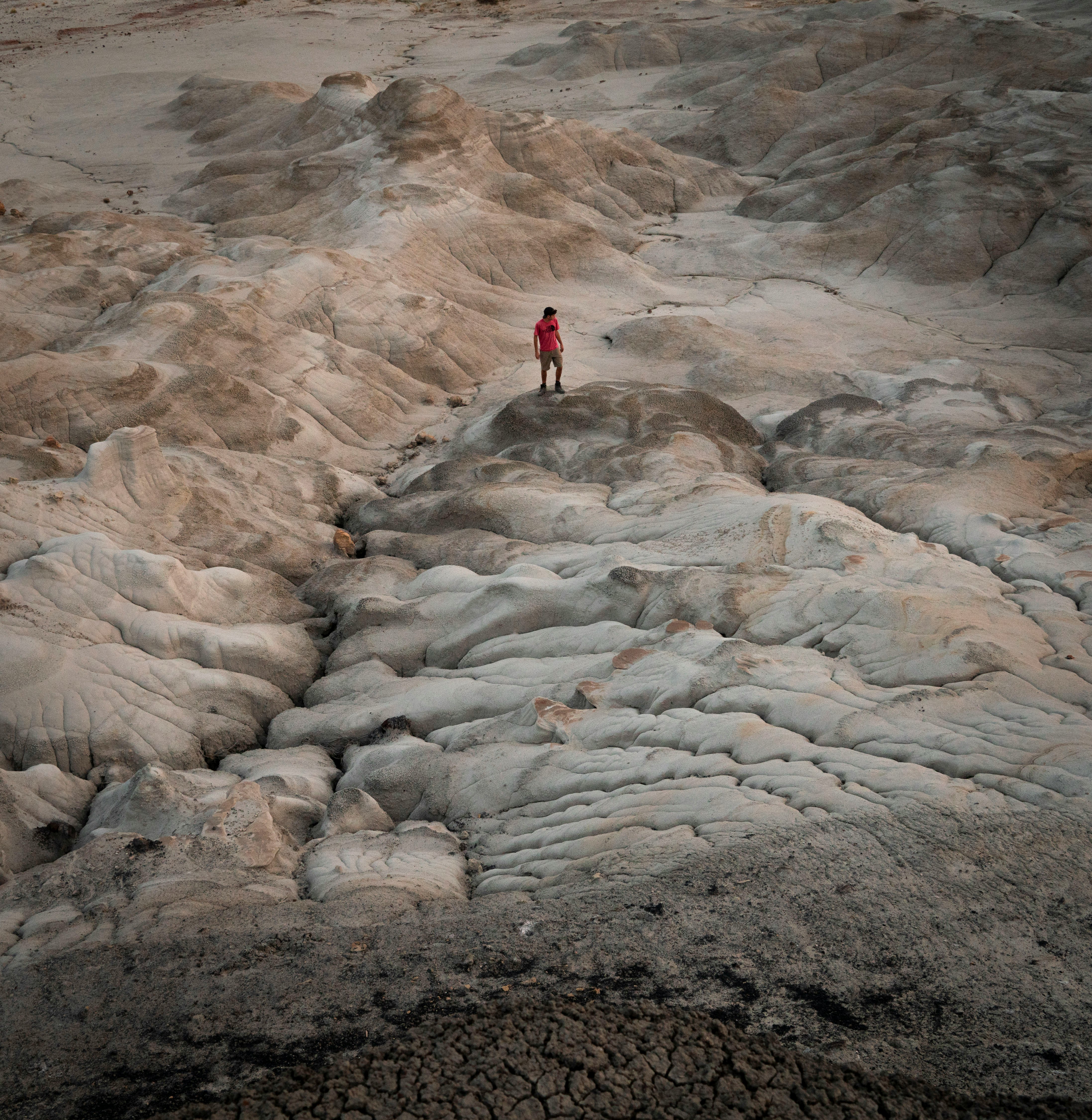 person in red jacket standing on rocky hill during daytime