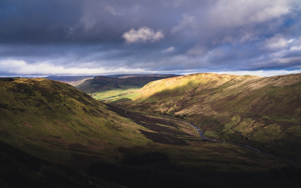 green and brown mountains under white clouds and blue sky during daytime