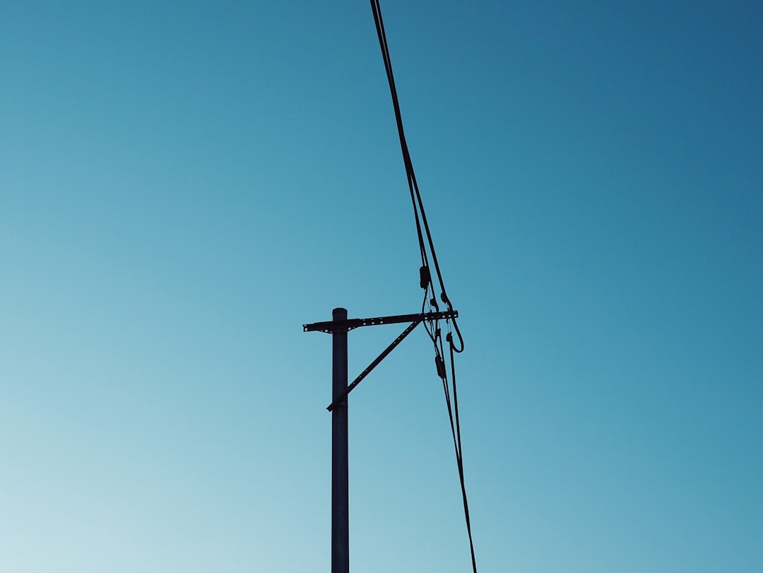 black electric post under blue sky during daytime