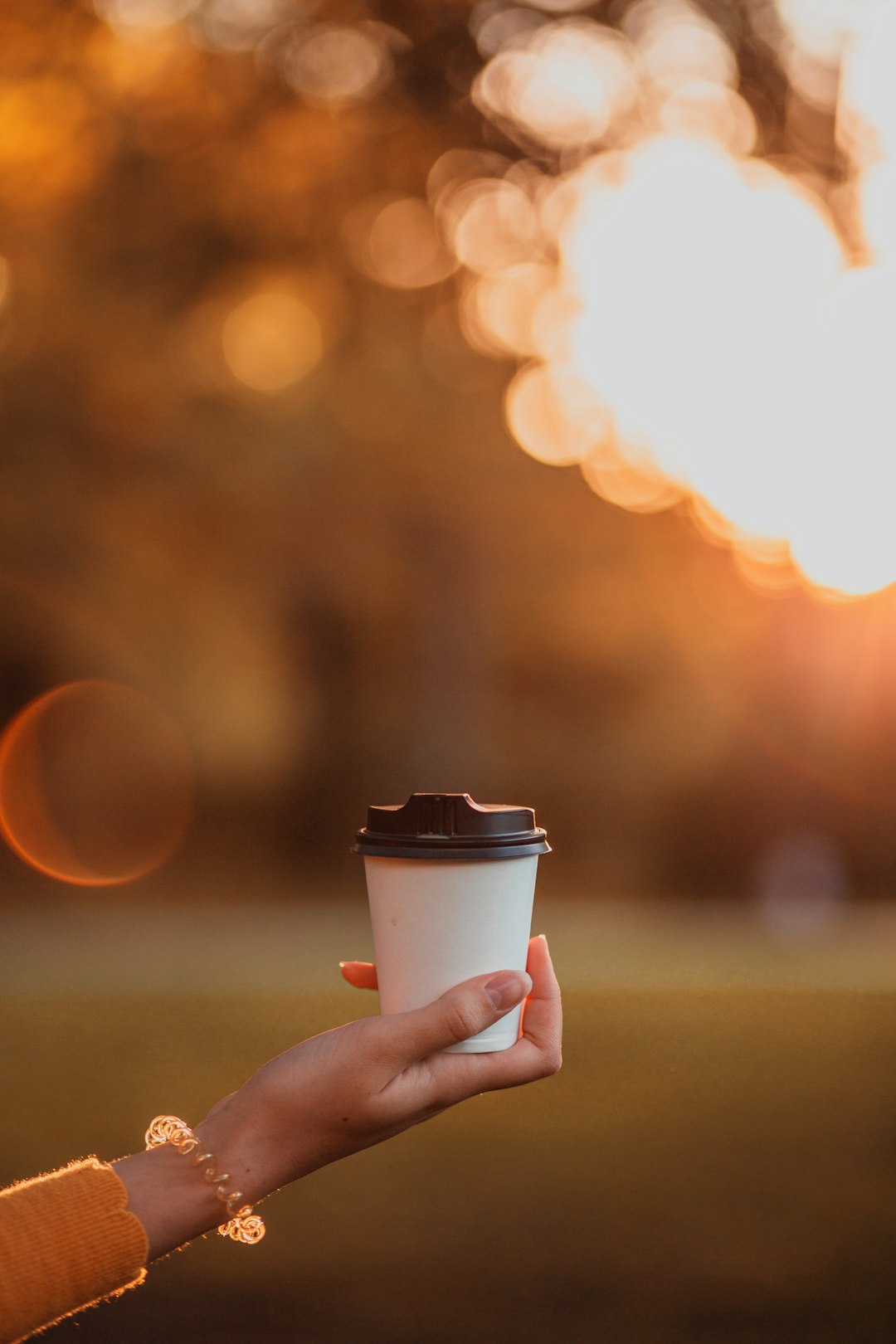 person holding white disposable cup during night time