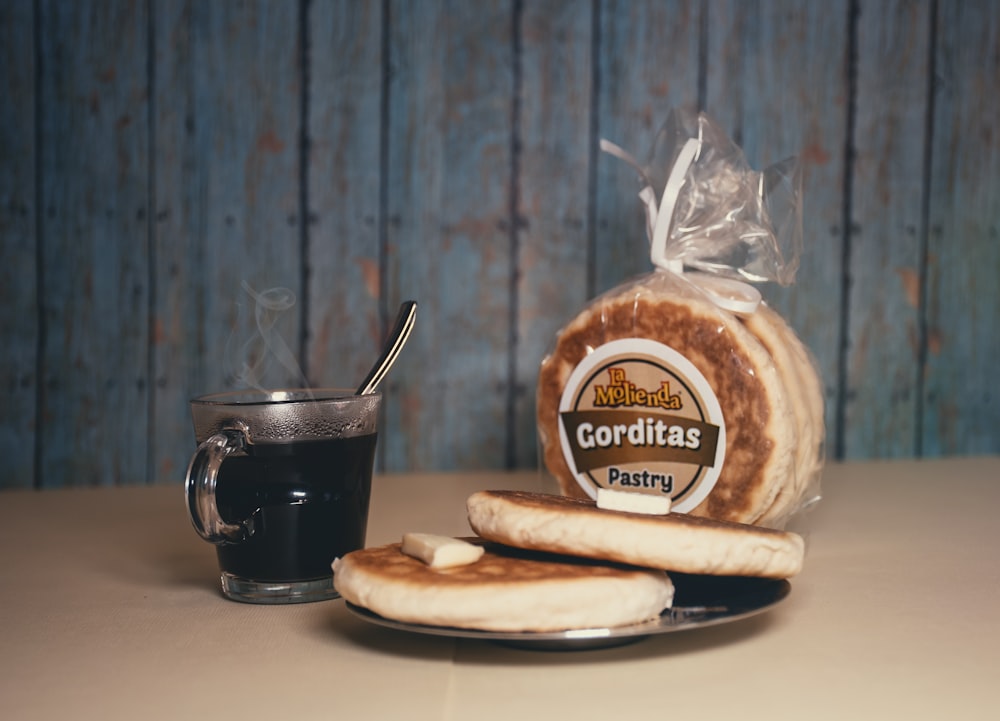 black ceramic mug beside brown bread on white ceramic plate