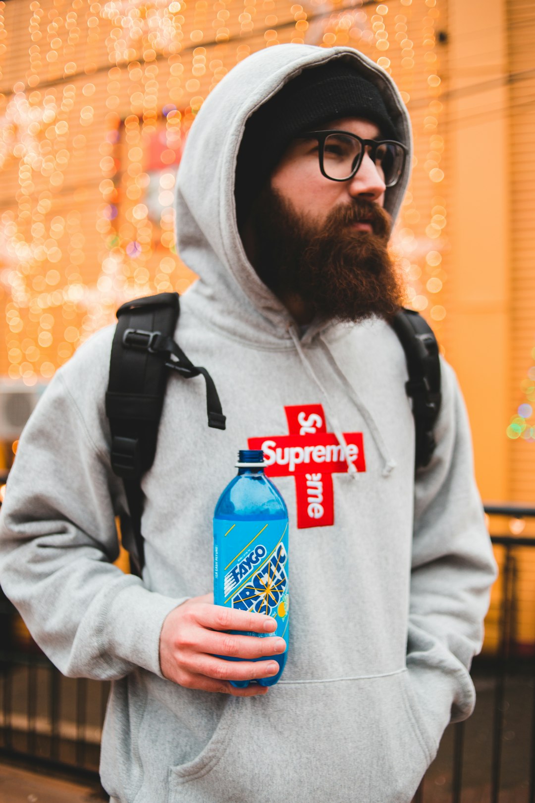 man in gray hoodie holding blue bottle