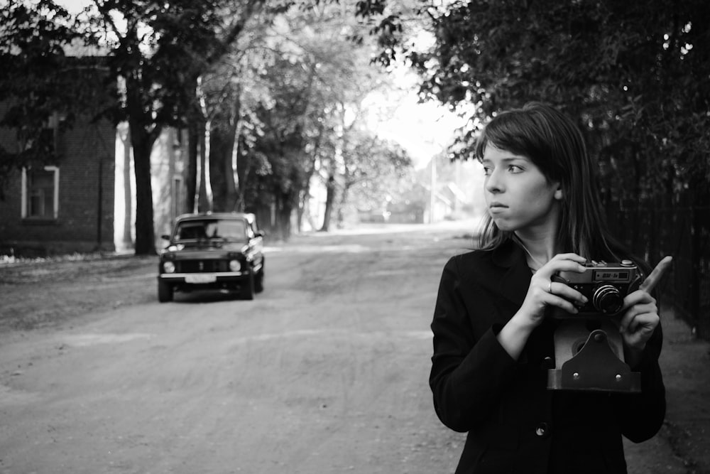 woman in black coat standing near black car