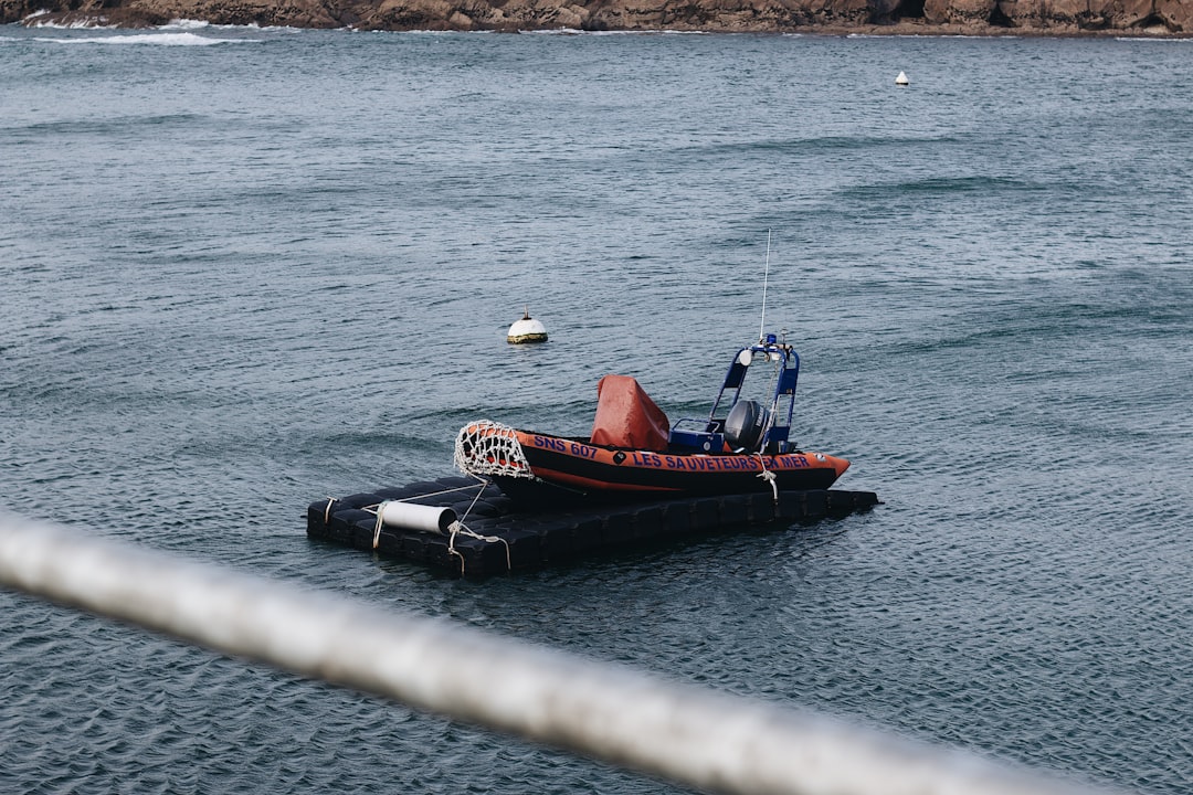 man in red shirt riding on red and black boat on body of water during daytime