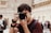 man in red and black crew neck t-shirt holding black nikon dslr camera