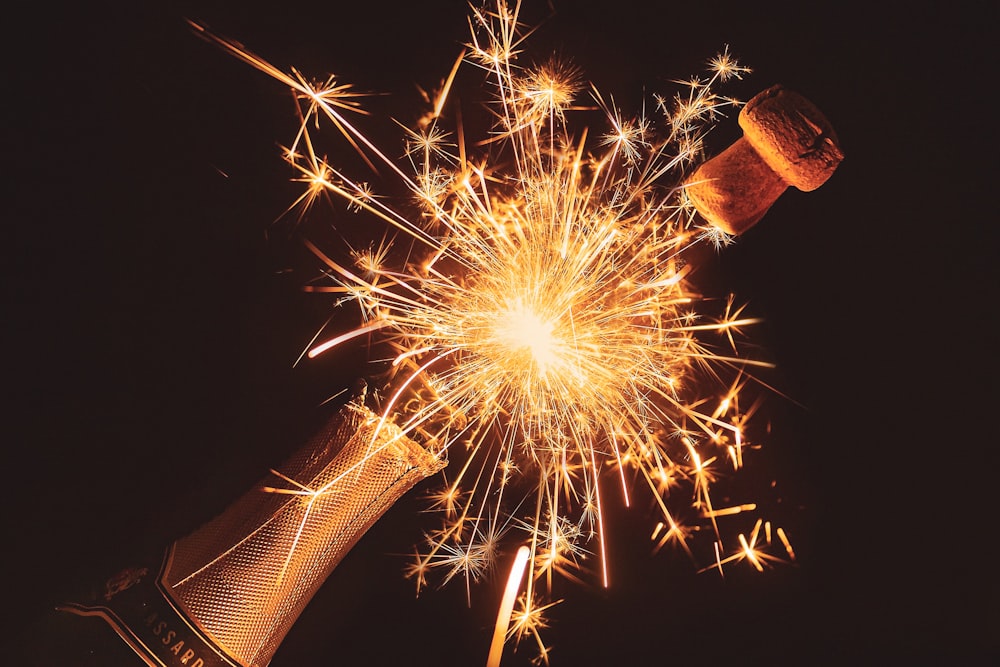 A montage of a champagne cork popping and a sparkler sending out sparks.