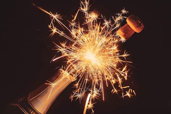 A montage of a champagne cork popping and a sparkler sending out sparks.