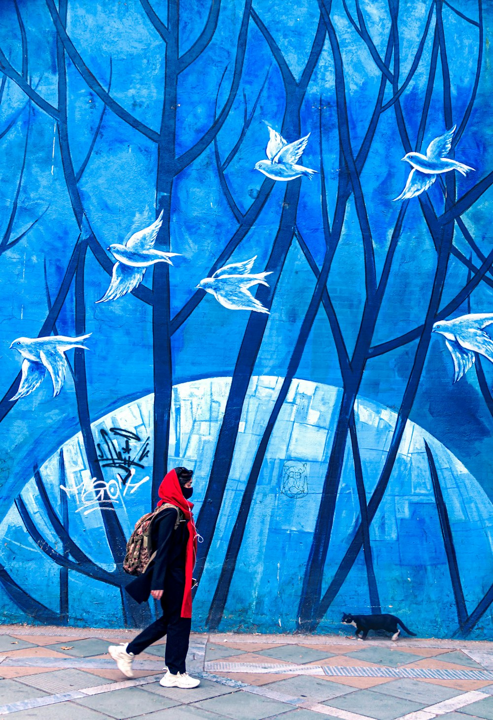 Mujer con abrigo rojo de pie sobre tela azul y blanca con estampado de estrellas