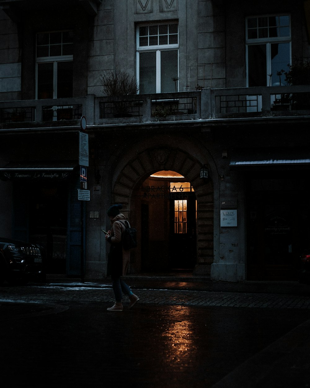 woman in black jacket walking on sidewalk during night time