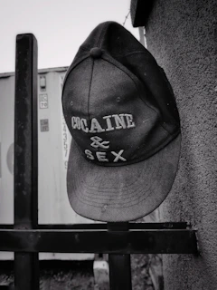 A sleek baseball cap hanging on a vintage hook against a brick wall