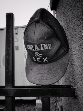 A sleek baseball cap hanging on a vintage hook against a brick wall
