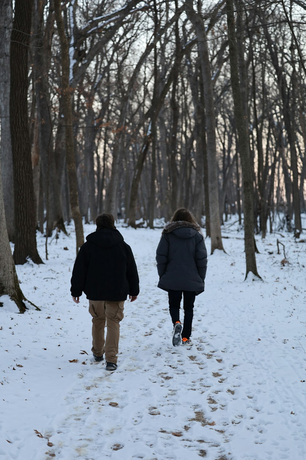 man and woman walking on snow covered ground during daytime