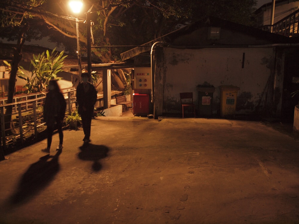 man in black jacket and pants walking on sidewalk during night time