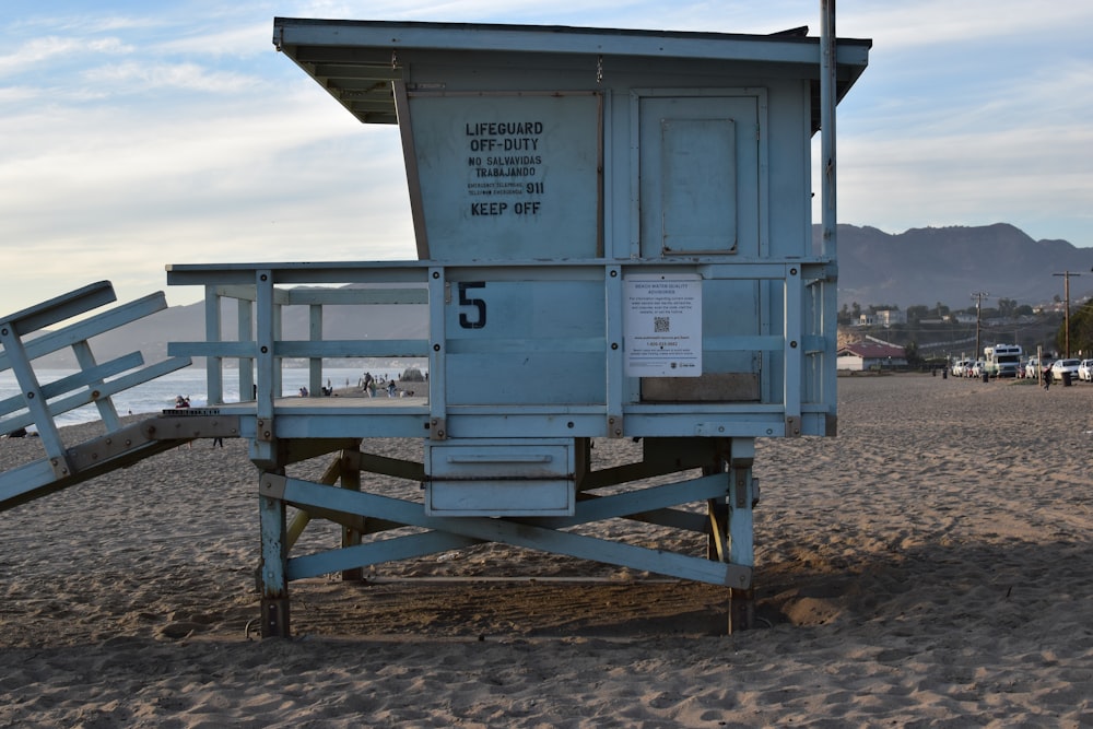blue and white wooden lifeguard house on brown sand during daytime