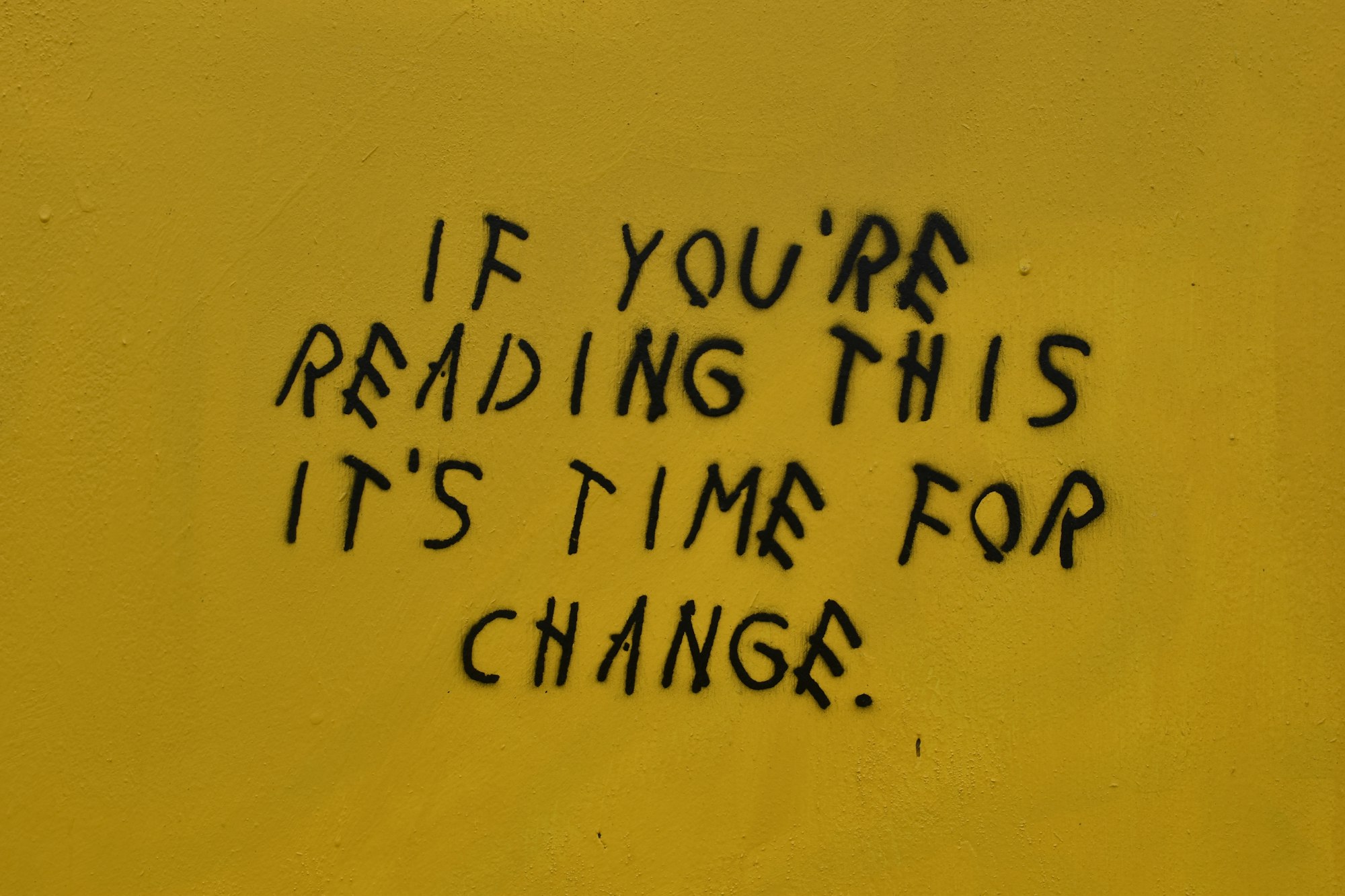 the words "if you're reading this it's time for change." scrawled in black on a wall
