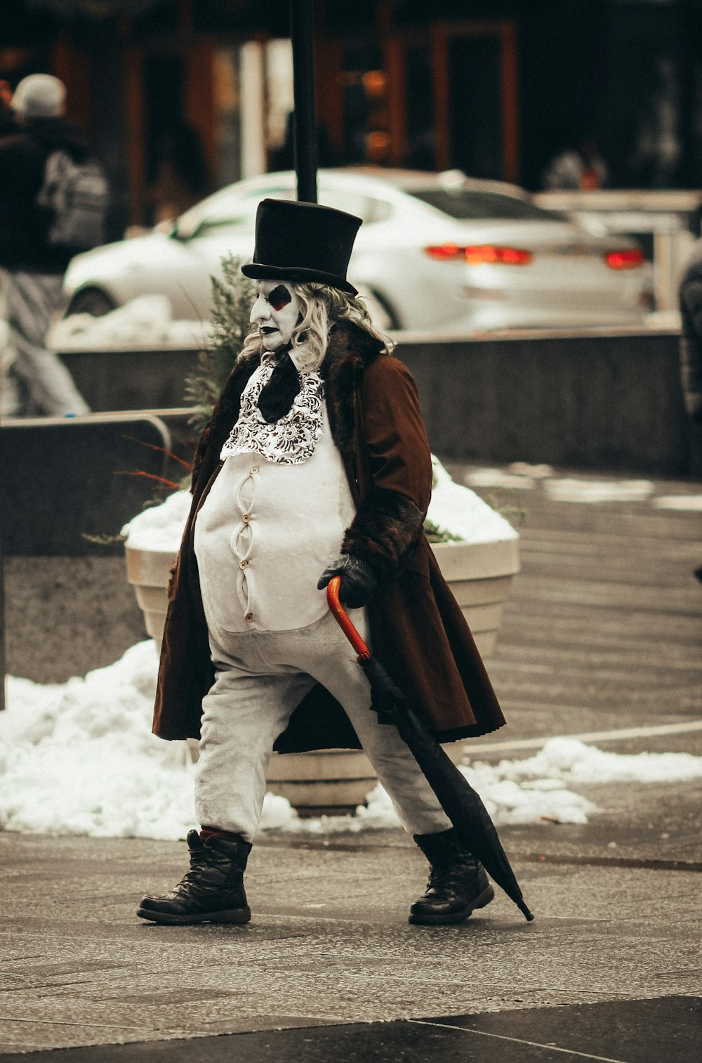 person in brown coat and black pants wearing black hat