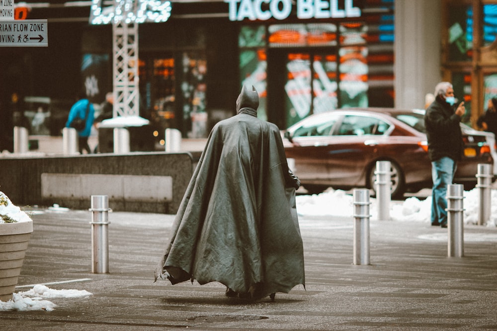 Persona con túnica gris sentada en la acera durante el día