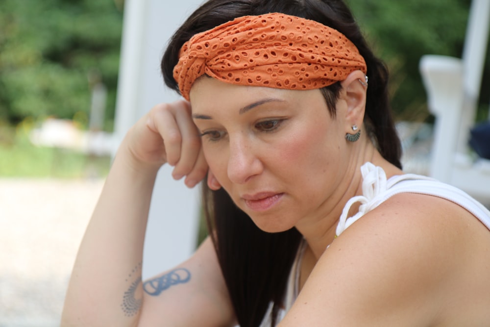 a woman wearing an orange headband looking at her cell phone