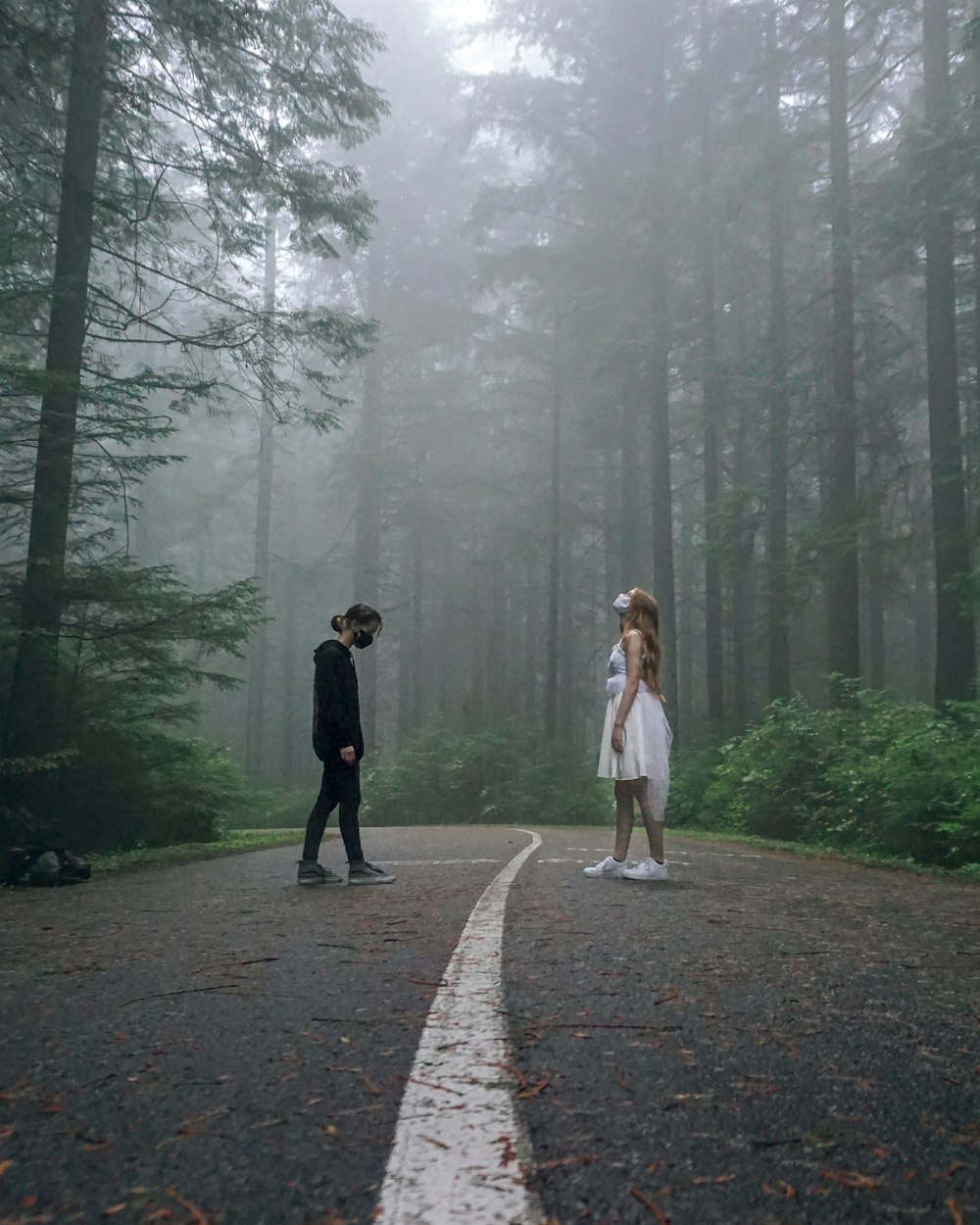 2 women walking on pathway between trees during daytime