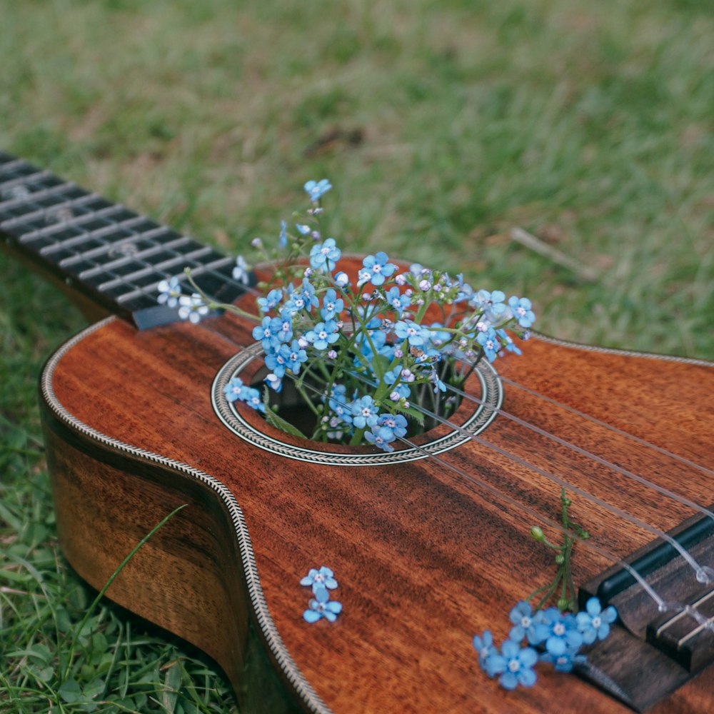Guitarra acústica marrón con flor blanca y verde en la parte superior