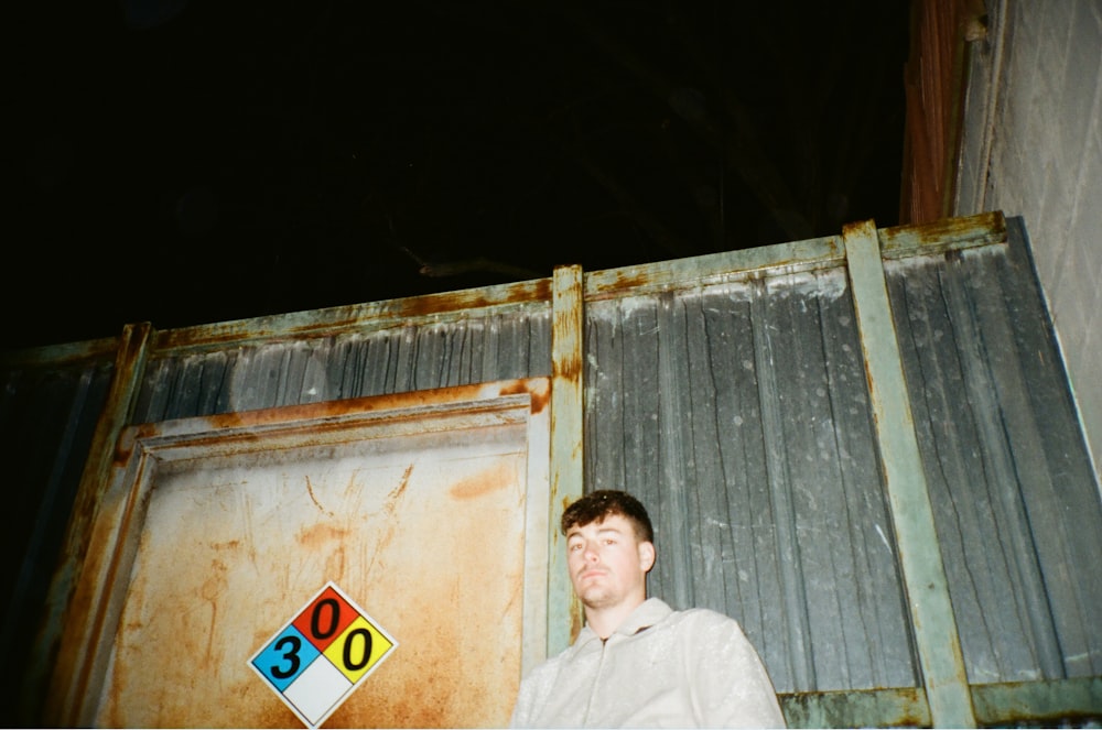 man in white dress shirt standing near brown wooden wall