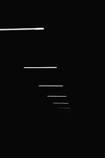 Vertical close-up of thin horizontal lines subtly dividing an off-white background, symbolizing time and space.