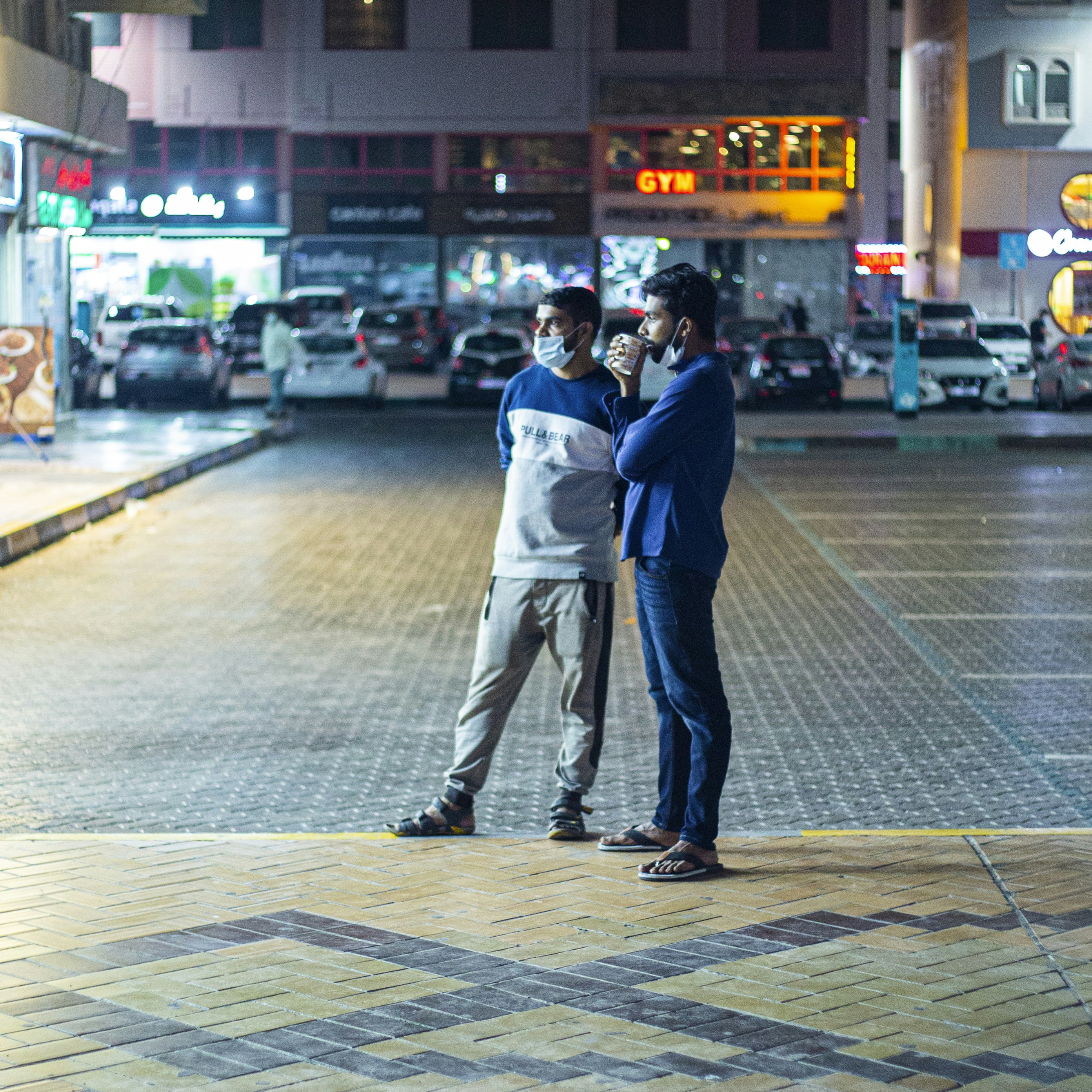 man in white shirt and blue denim jeans walking on sidewalk during night time