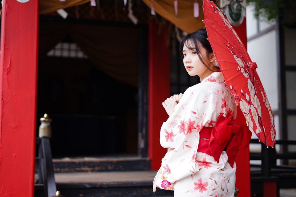 昼間の歩道に立つ白とピンクの花柄の着物を着た女の子