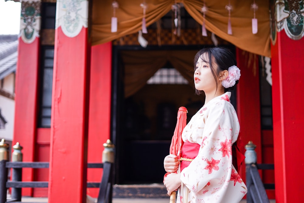 woman in white and red floral kimono holding red umbrella