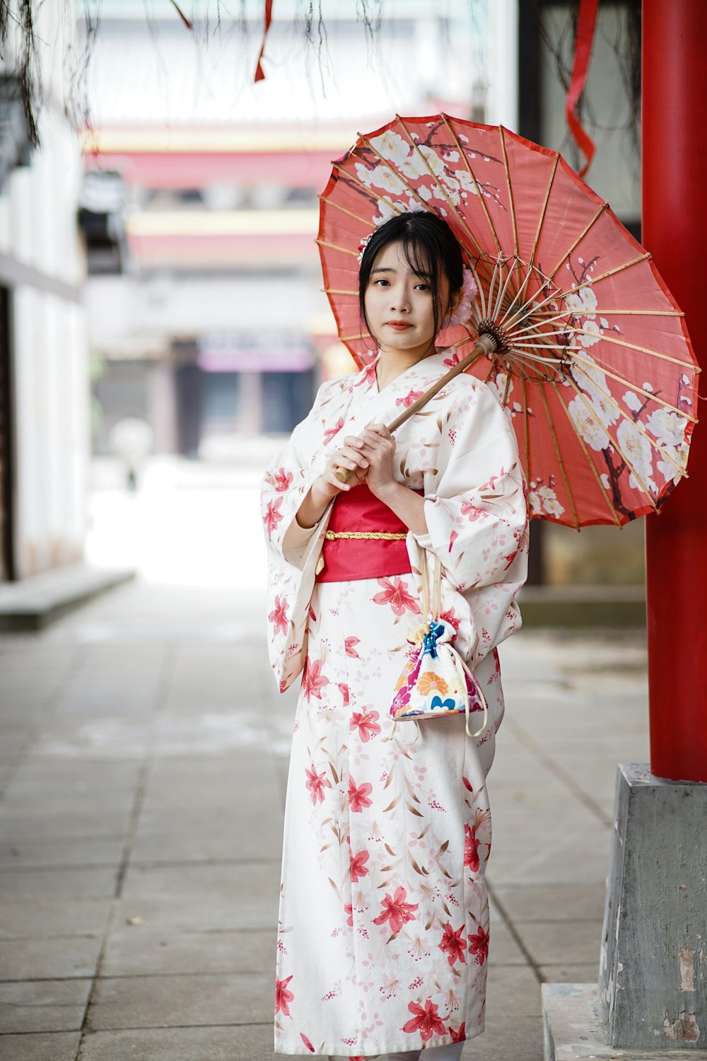 Mujer en kimono blanco y rojo sosteniendo paraguas