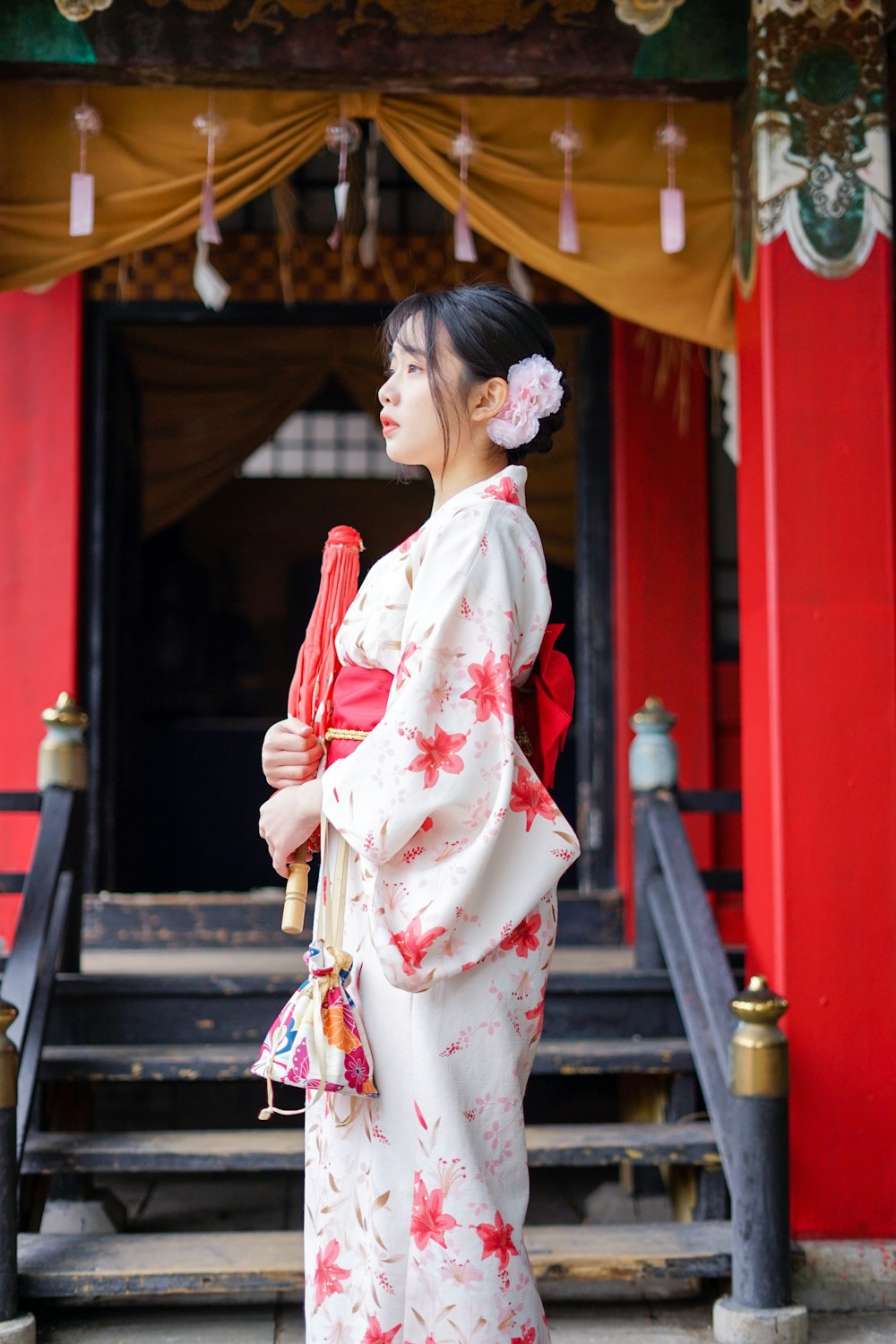 woman in white and pink floral kimono holding red umbrella