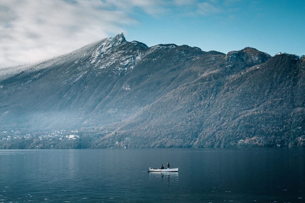 white boat on water near mountain during daytime