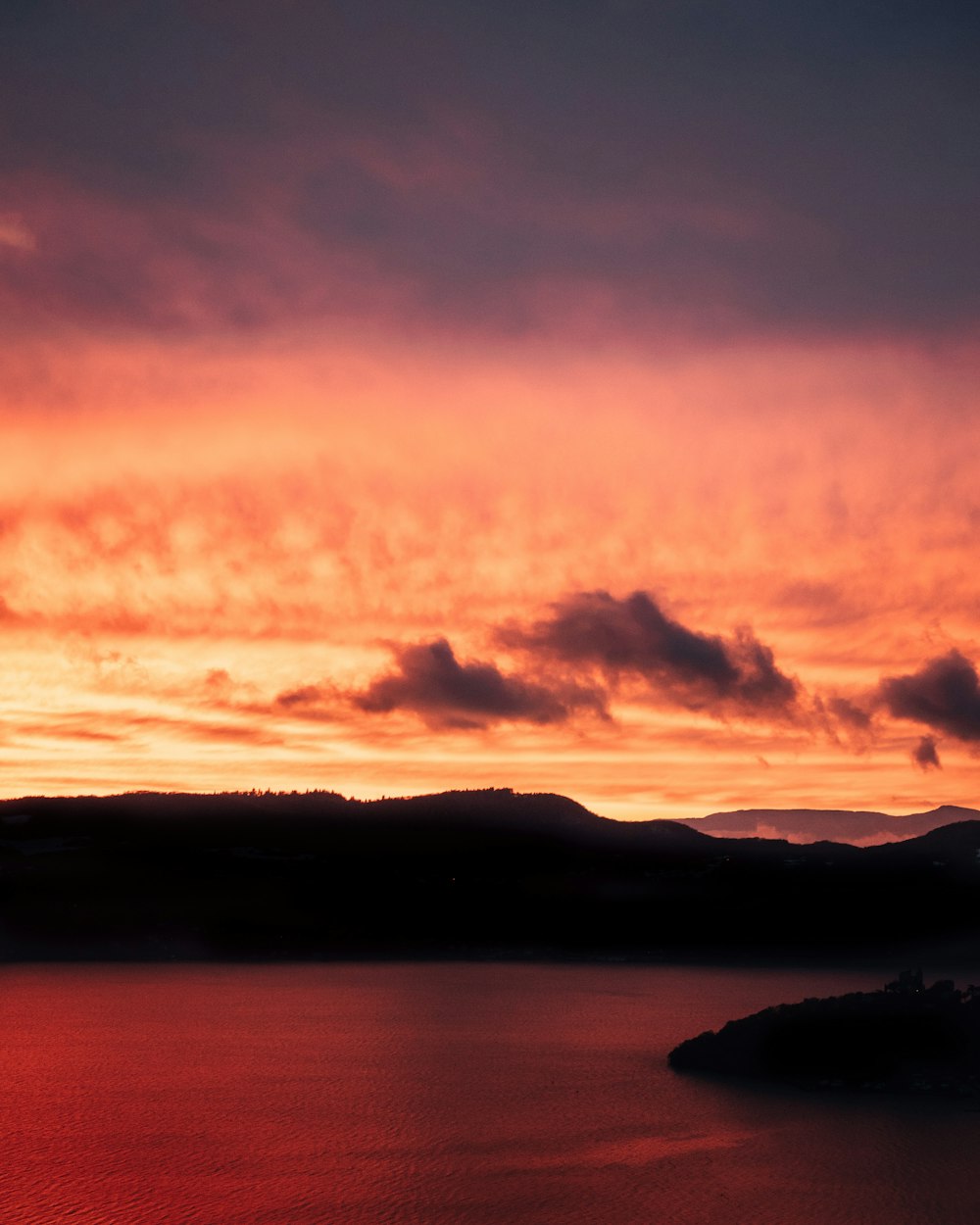 Silhouette de montagne près du plan d’eau au coucher du soleil