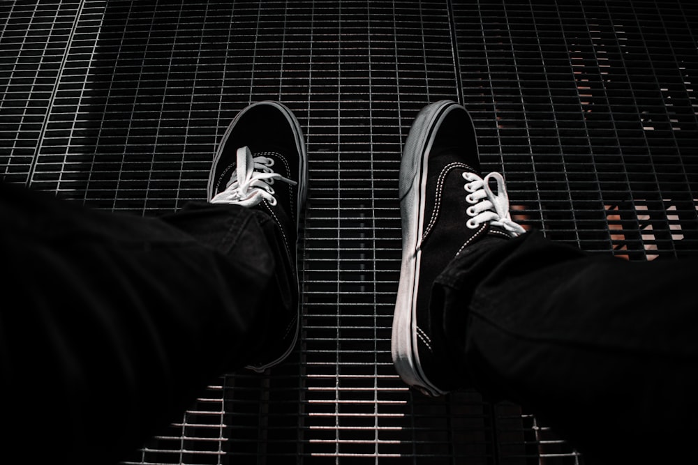 person in black pants wearing black and white sneakers