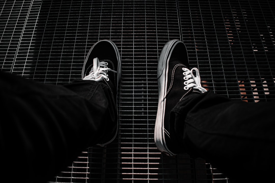 person in black pants wearing black and white sneakers