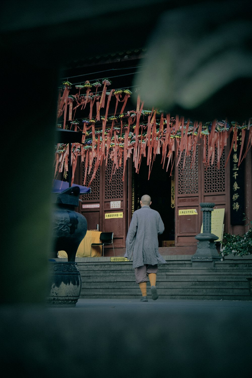 Mann im braunen Mantel, der tagsüber in der Nähe des rot-weißen chinesischen Tempels steht