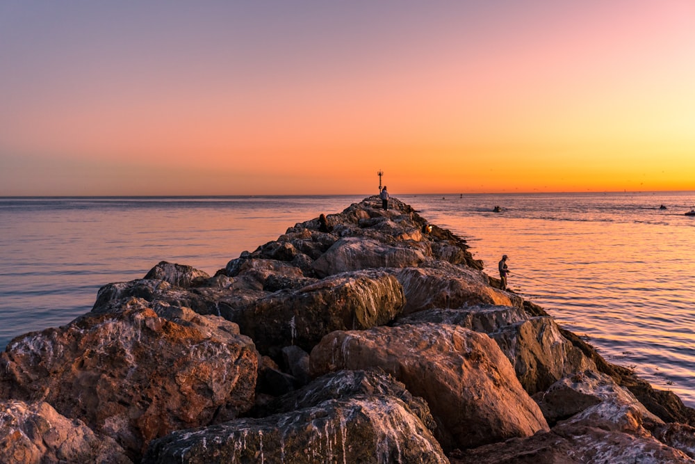 person standing on rock formation near sea during daytime